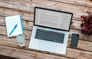 Picture of a macbook and a notebook with a blog on the screen